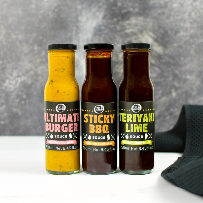 Three bottles of sauces with labels on a gray background