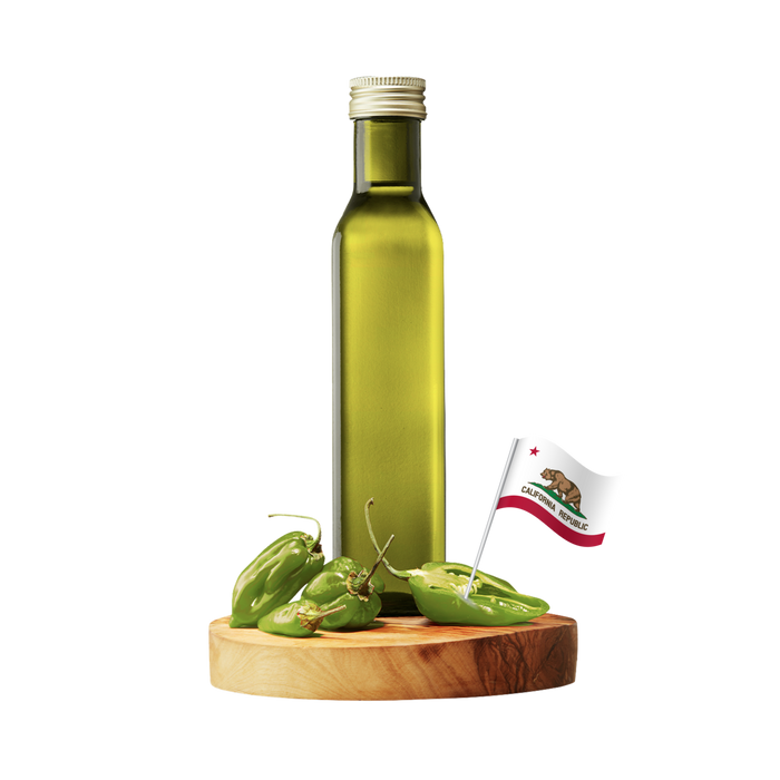 A tall olive-green glass bottle with a silver cap stands on a round wooden board with several green chili peppers and a small California flag.