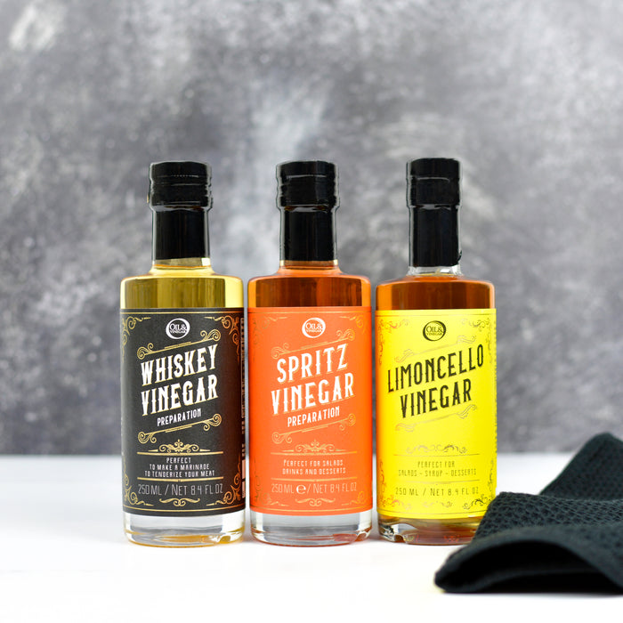 Three bottles of vinegar with colorful labels on a gray background