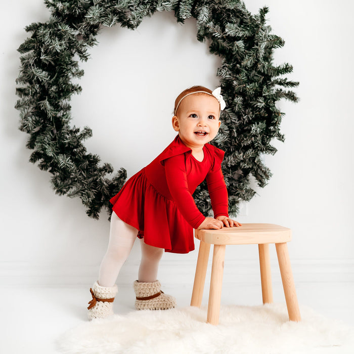 Baby wearing Kyte Baby Long Sleeve infant twirl Bodysuit in Cardinal