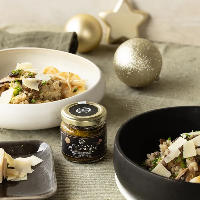 Olive and Truffle Spread jar with pasta dishes on a festive table setting.
