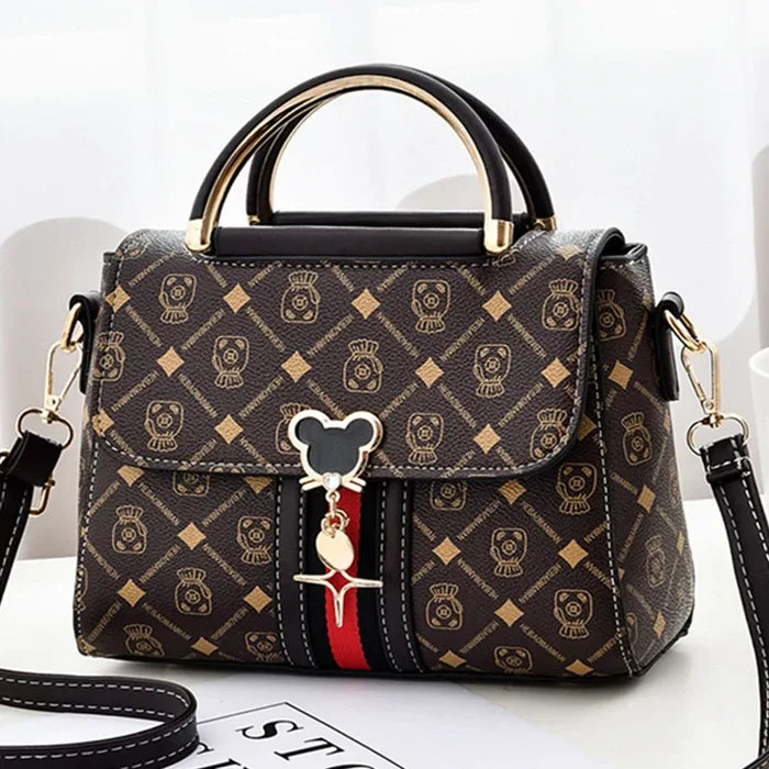 Designer handbag with a distinctive pattern and decorative charm on a white background