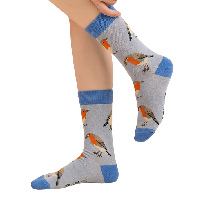 A pair of gray crew socks with blue cuffs, heels, and toes, featuring a pattern of robin birds, shown on a person's feet against a white background.