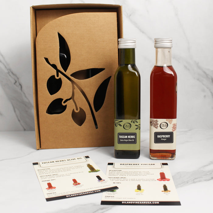 Two bottles of olive oil and vinegar with a decorative box on a white background
