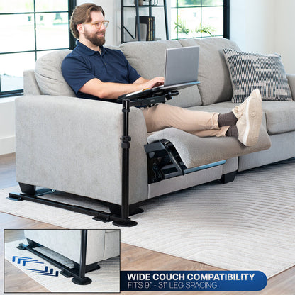 Man using a laptop on a couch with a portable laptop desk, surrounded by a modern living room.