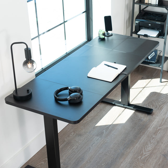 Modern desk setup with a lamp, headphones, and a tablet in a bright room.