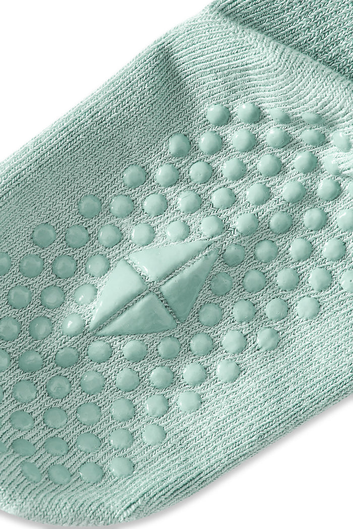Bottom of a a sock in the color Sage with grips.