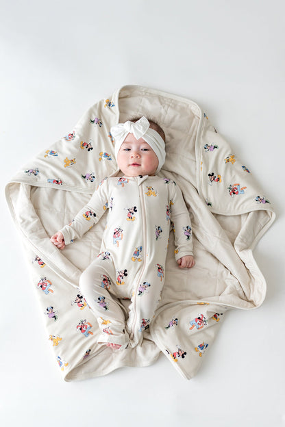 Baby wearing a Mickey Mouse footie laying on a matching baby blanket