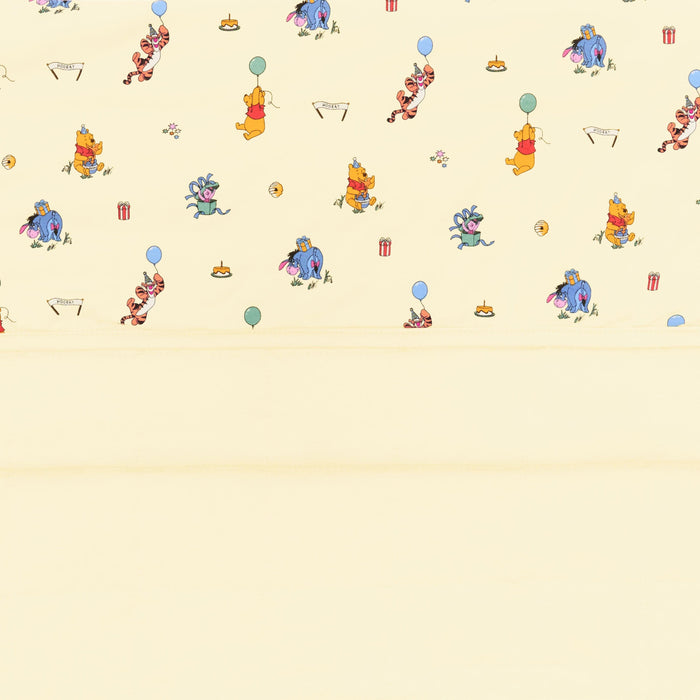 Close up of the Baby Blanket in Winnie the Pooh Celebration showing the light yellow quilted backing and smooth printed top layer