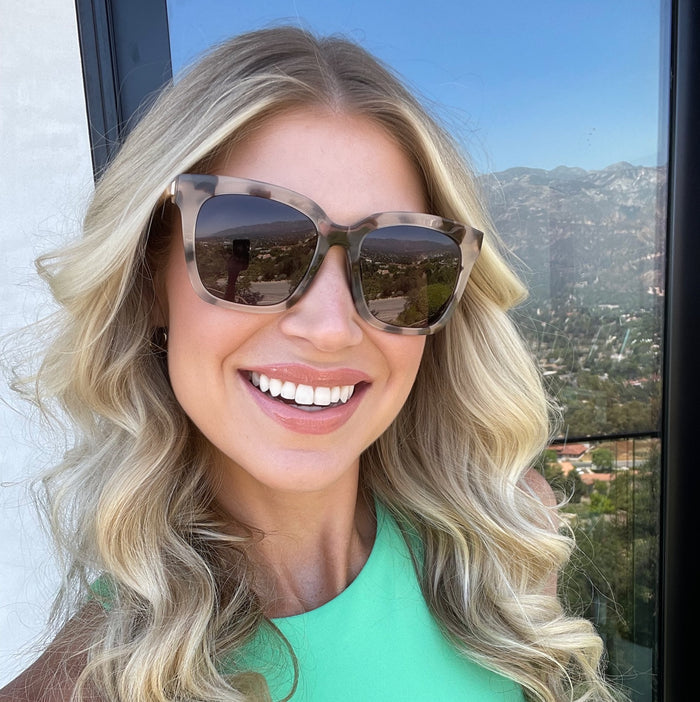 UGC - customer content - female with curly blonde hair smiling wearing diff eyewear bella square sunglasses with a cream tortoise frame and grey gradient polarized lenses