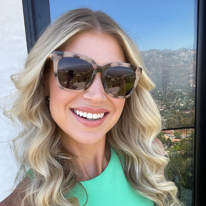 UGC - customer content - female with curly blonde hair smiling wearing diff eyewear bella square sunglasses with a cream tortoise frame and grey gradient polarized lenses