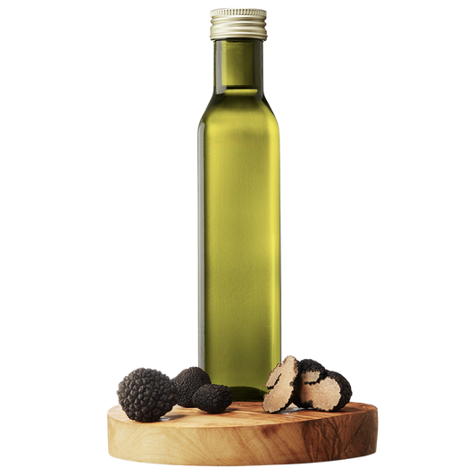 A bottle of Black Truffle Extra Virgin Olive Oil on a wooden platform with whole black truffles beside it.