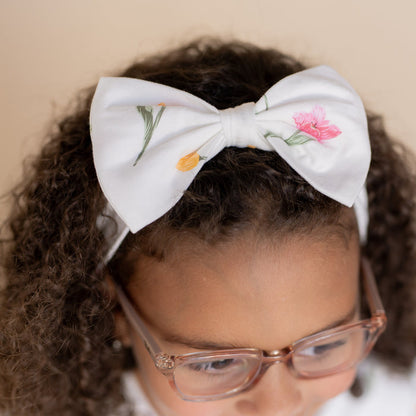 Close up of the Bow Headband in Tulip shown in the hair of a young girl model