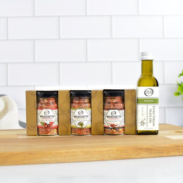Set of Bruschetta seasoning jars and a bottle of olive oil on a wooden surface with a white tiled wall background.