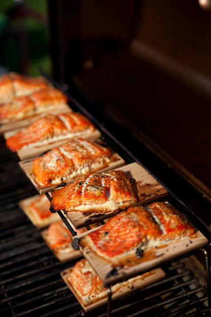 Salmon filets on wooden grilling planks being cooked on a grill.