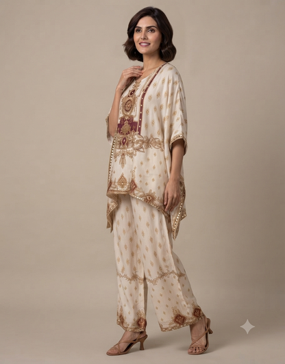 Model wearing an elegant cream-colored printed tunic and matching trousers set against a muted beige background.