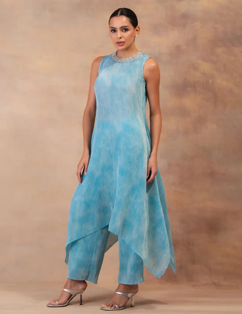 Model wearing the 'CLOUD DRIFT' tunic drape-dress set with matching pants, crafted in micro-pleated georgette satin with gold foil detailing in Singapore.
