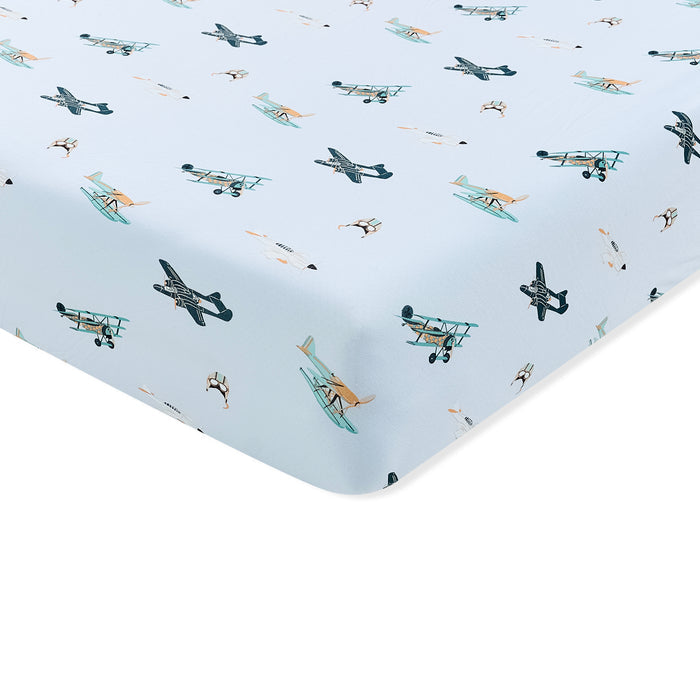 Corner of the Crib Sheet in Take Off shown on a mattress