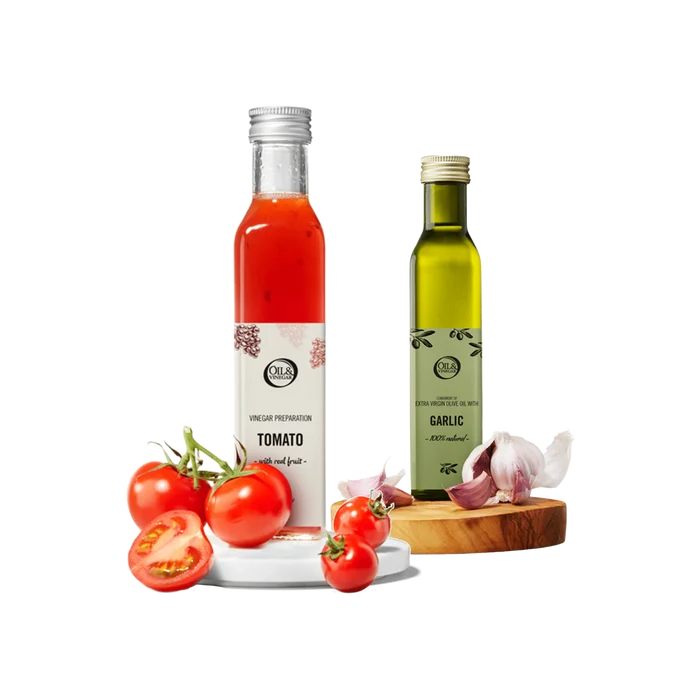 Two bottles of tomato vinegar and garlic olive oil with tomatoes and garlic