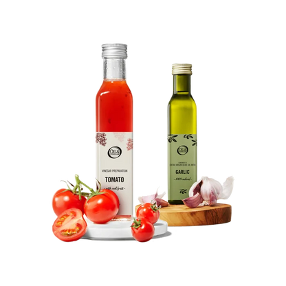 Two bottles of tomato vinegar and garlic olive oil with tomatoes and garlic