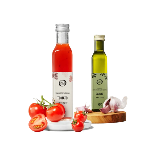 Two bottles of tomato vinegar and garlic olive oil with tomatoes and garlic