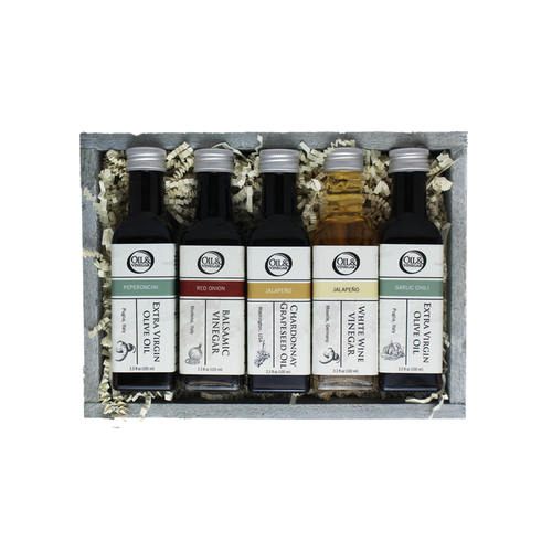 Set of five olive oil and vinegar bottles in a wooden box with decorative elements.