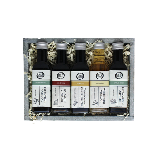 Set of five olive oil and vinegar bottles in a wooden box with decorative elements.