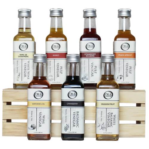 Seven assorted bottles of Oil & Vinegar on a wooden crate