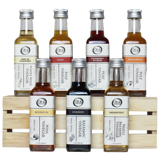 Seven assorted bottles of Oil & Vinegar on a wooden crate