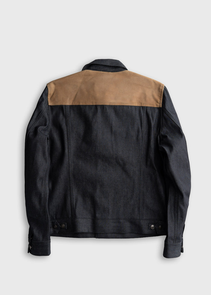 Dark denim jacket with tan shoulder panel, back view. Features adjustable cuffs and waistband, creating a stylish, modern look.