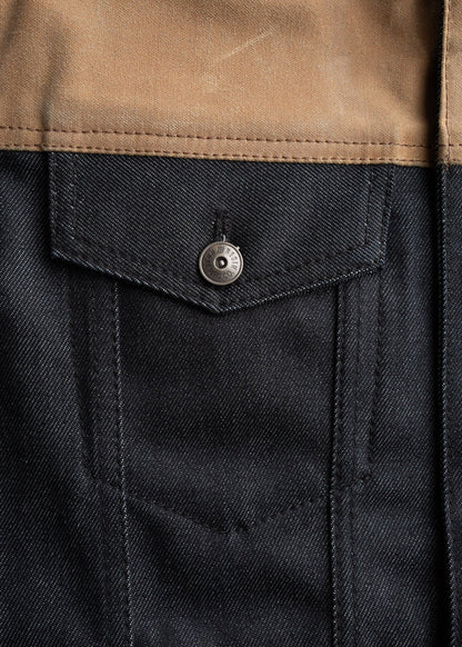 Close-up of a denim jacket pocket with a metal button and brown fabric detail, showcasing texture and stitching.