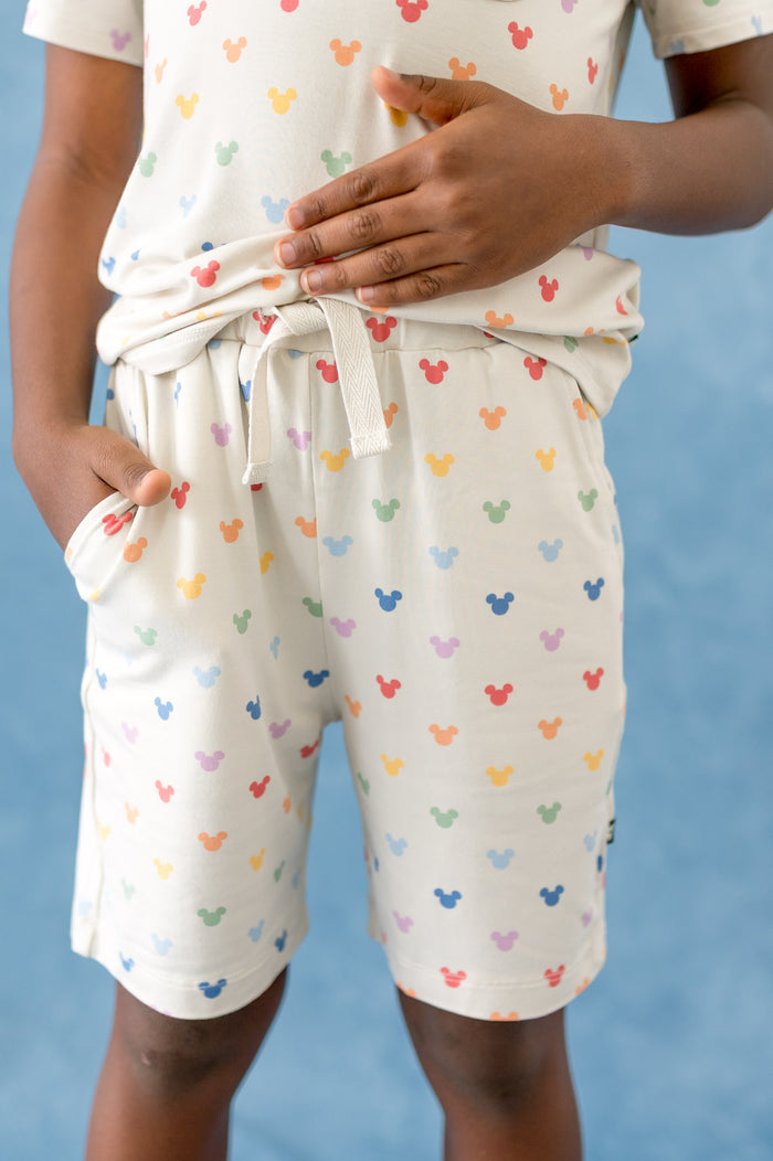 Person wearing a cream outfit with colorful mickey head patterns on a blue background