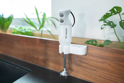 Der Unold ESGE-Zauberstab® M 122 De Luxe steht auf einer hölzernen Arbeitsplatte in einer modernen Küche mit grünen Topfpflanzen und natürlichem Licht, das durch das Fenster fällt.