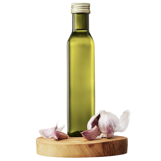A bottle of Garlic Extra Virgin Olive Oil on a wooden platform with whole garlic cloves around it.