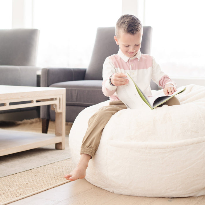 Child sitting on a Saranoni Bean Bag, enjoying a cozy read in a bedroom setting.