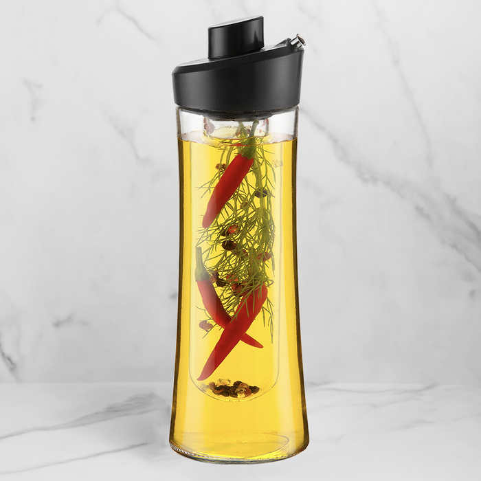 Herb Oil infuser with a black lid filled with oil, peppers, and herbs on a white background.