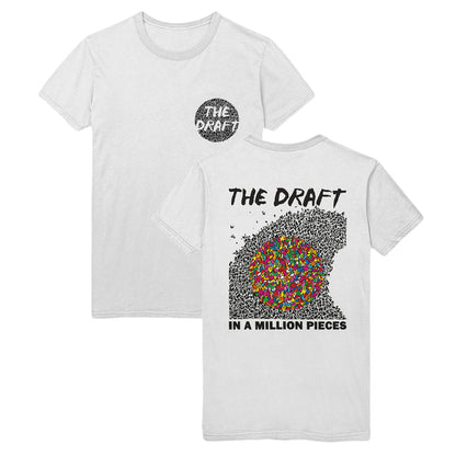 Two sides of the white t-shirt are displayed. The front has "THE DRAFT" printed over a circle with black shards of glass in the top right corner of the shirt. The back of the shirt has "THE DRAFT" printed in the top center with a drawing of several different black pieces that make up a wave shape. Over the wave is a colorful circle made up of rainbow pieces. Below this drawing reads "IN A MILLION PIECES" in a bold, black font.