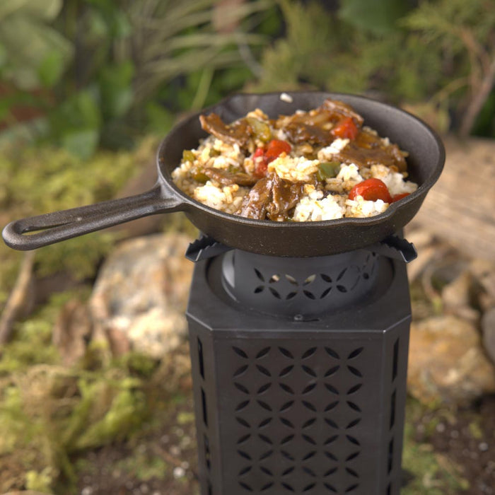 InstaFire Inferno Outdoor Biomass Stove cooking food on a cast iron pan outdoors