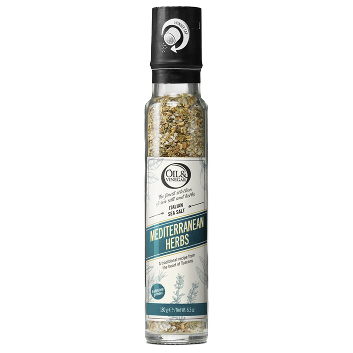 A clear glass bottle with a black lid containing ground Italian sea salt with Mediterranean herbs visible through the bottle, labeled 'MEDITERRANEAN HERBS'.
