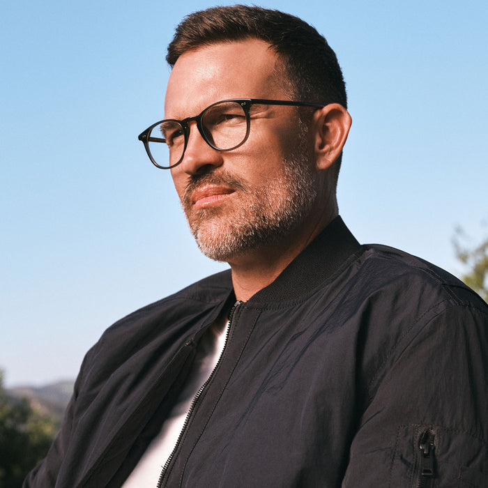 lifestyle - on model male wearing diff eyewear jaxson round glasses with a black acetate frame and prescription lenses angled view