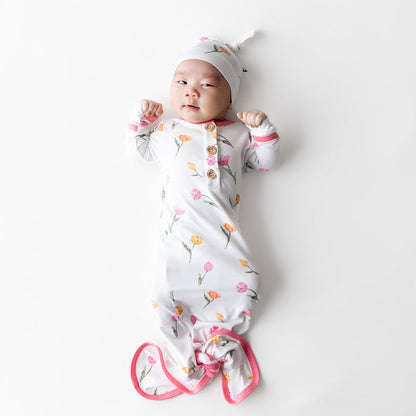 Newborn laying on a white surface wearing the Knotted Gown with Hat Set in Tulip