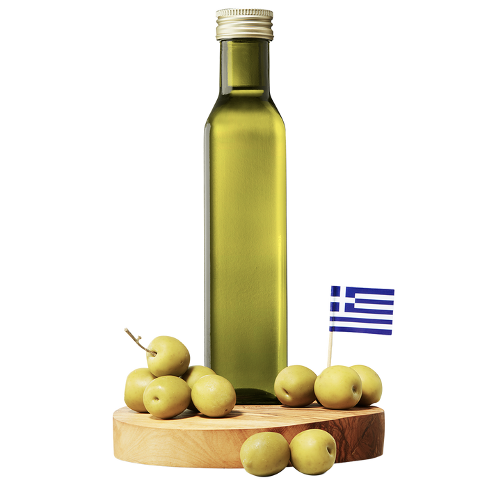 A bottle of extra virgin olive oil with a small Greek flag and fresh olives on a wooden board.