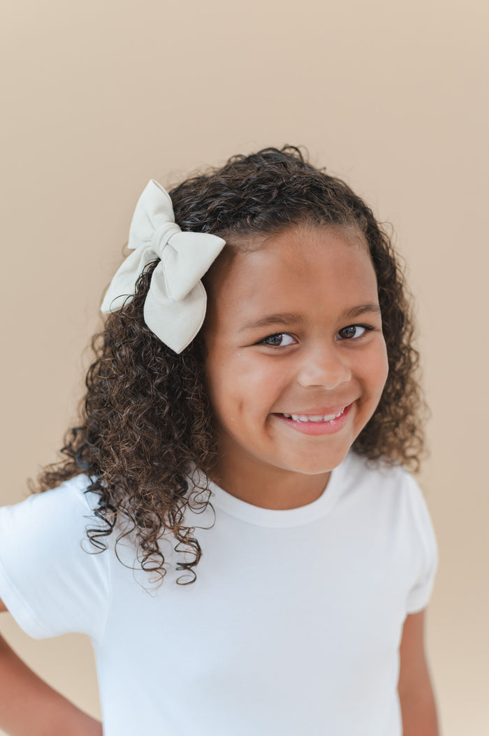 Smiling girl wearing the Large Alligator Clip Bow in Oat in her hair