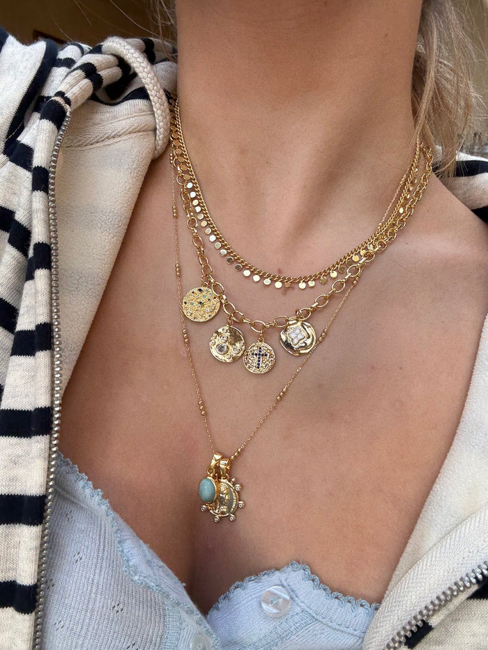 Layered gold necklaces styled for a cool jewellery stack