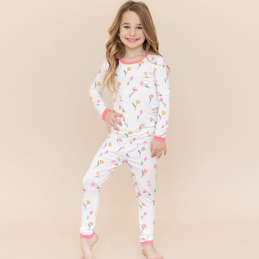 Young girl modeling the Long Sleeve Pajamas in Tulip standing in front of a light neutral background