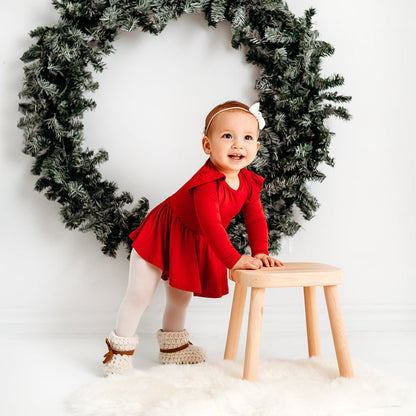 Baby wearing Kyte Baby Long Sleeve infant twirl Bodysuit in Cardinal