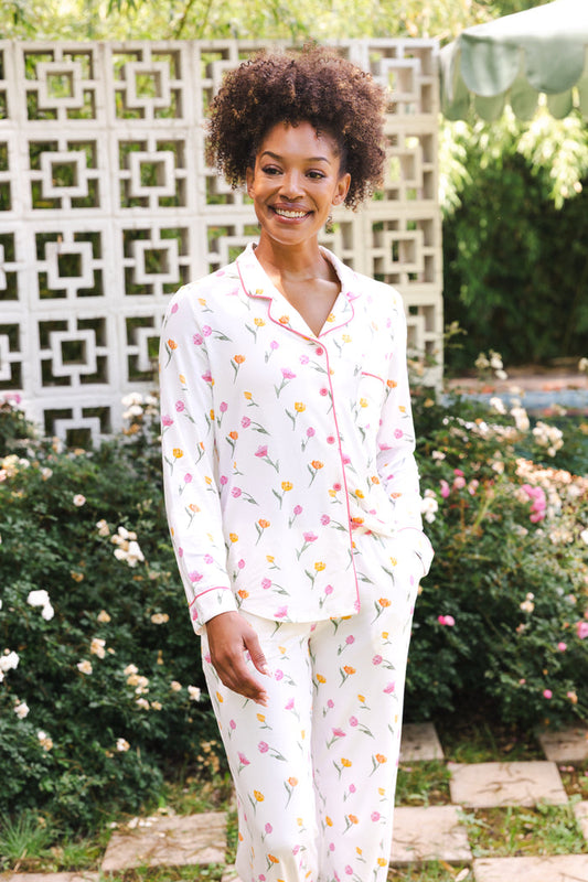 Woman wearing a floral pajama set standing outdoors with greenery in the background