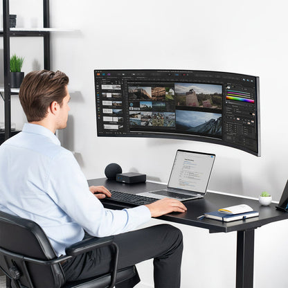 Person working at a desk with a large monitor mounted on the wall.