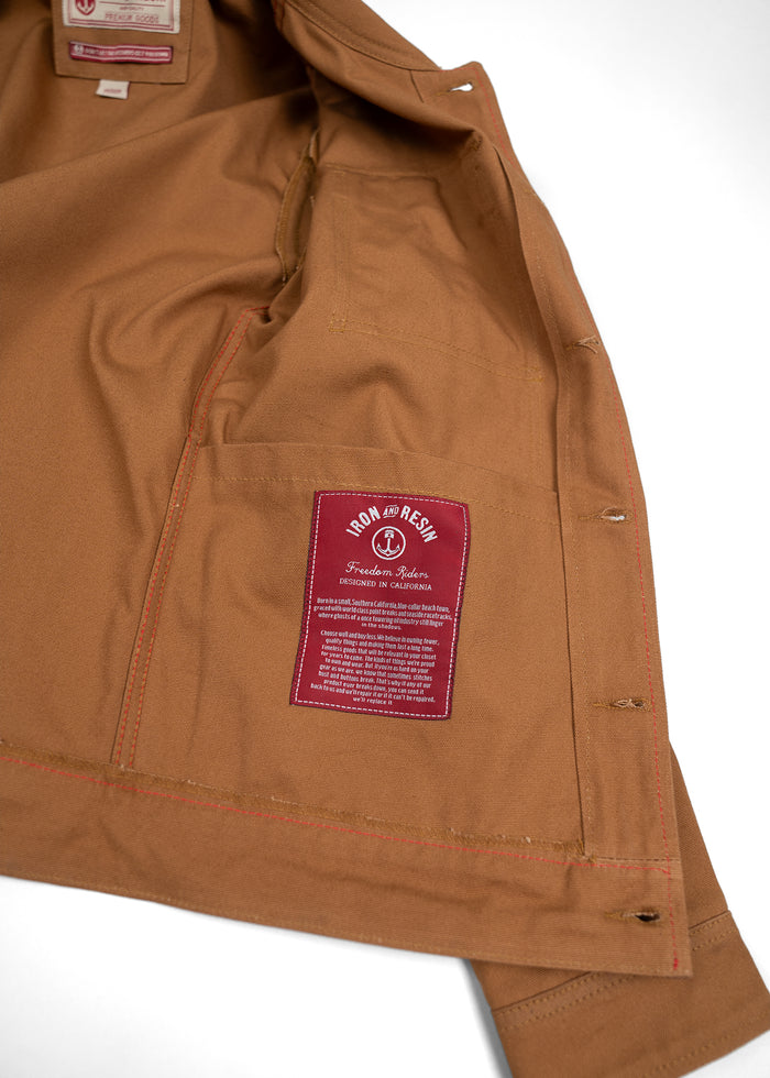 Brown jacket interior with red "Iron and Resin" label, highlighting "Freedom Riders" design, crafted in California.