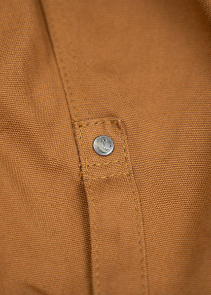 Close-up of a brown fabric with a metal button, showcasing detailed stitching and texture, highlighting craftsmanship.